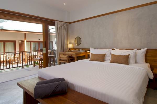 Innenansicht eines Zimmers im Banana Fan Sea Resort mit einem großen Bett, zwei Nachttischen und einem Schreibtisch.