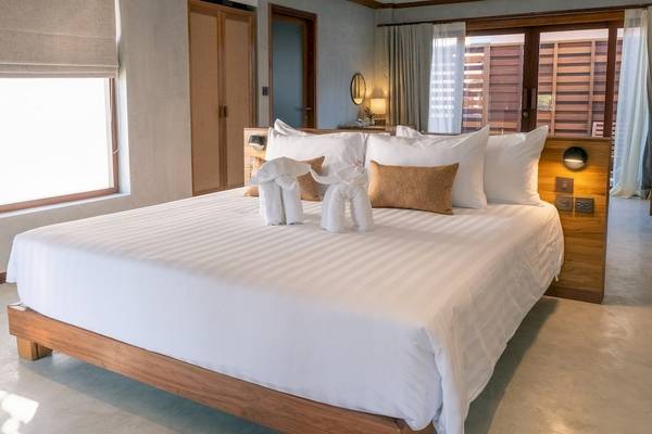 Ein stilvolles Hotelzimmer im Banana Fan Sea Resort mit einem großen Bett, weißen Laken und dekorativen Elefantenfiguren.