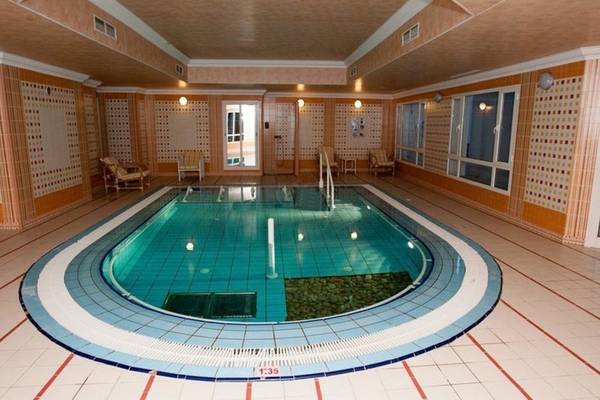 Innenansicht des Schwimmbads im Mahdia Palace Thalasso, mit blauen Kacheln und Lounge-Stühlen.