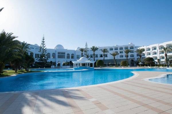 Außenpool des Mahdia Palace Thalasso Hotels mit weißem Gebäude und Palmen im Hintergrund.
