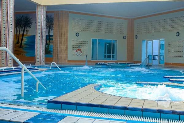 Innenpool im Mahdia Palace Thalasso mit tropischen Wandmalereien und Wasserfällen.