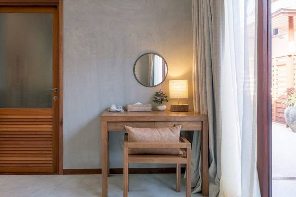 Ein schlichtes Hotelzimmer mit einem Schreibtisch, einer Lampe und einem Spiegel.