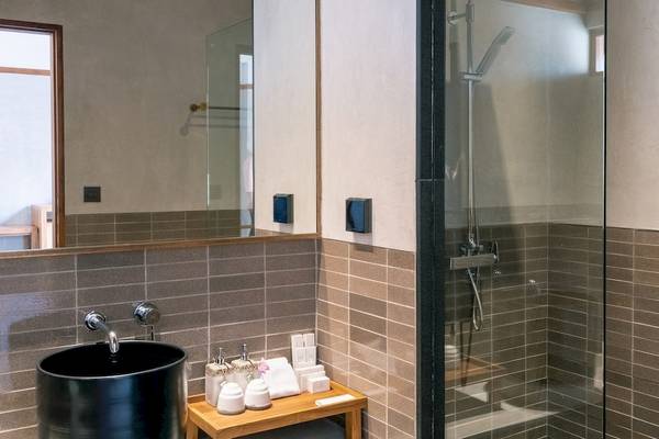 Badezimmer im Banana Fan Sea Resort mit schwarzen Waschbecken, Glasdusche und gefliester Wand.