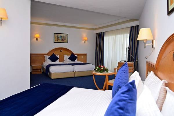 Innenansicht eines Doppelzimmers im Mahdia Palace Thalasso mit zwei Betten, Tisch und Dekor.