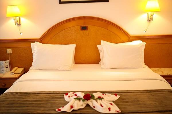 Hotelzimmer im Mahdia Palace Thalasso mit weißem Bettzeug, Kopfteil und Tischlampen.