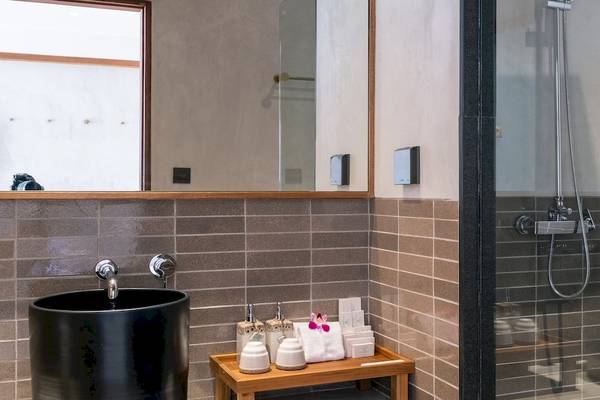 Badezimmer im Banana Fan Sea Resort mit einem schwarzen Waschbecken, einem Spiegel und einer Glasdusche.