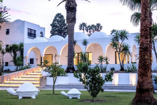 Außenansicht des Hotels Orangers Garden Villas & Bungalows mit weißen Gebäuden und beleuchteten Stufen