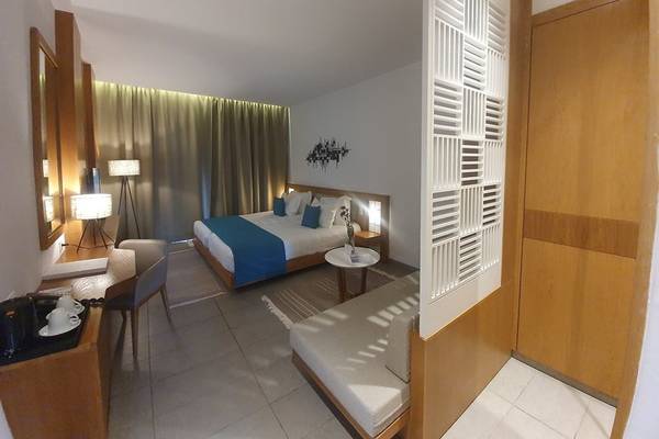 Innenansicht eines Hotelzimmers von Orangers Garden Villas & Bungalows mit Bett, Tisch, Stühlen und Dekor.