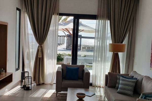 Wohnzimmer mit großer Fensterfront und Blick auf den Strand und das Meer.