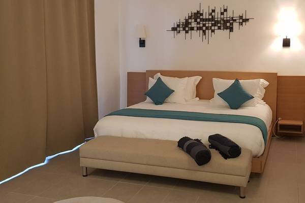 Zimmer im Orangers Garden Villas & Bungalows mit einem großen Bett, blauen Kissen und einer gemusterten Wand.