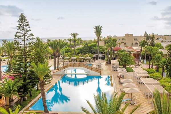 Außenansicht des Aldiana Club Djerba Atlantide Resorts mit Swimmingpool und Sonnenschirmen.