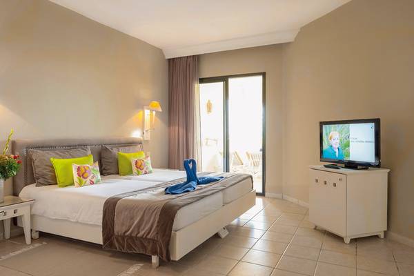Hotelzimmer im Aldiana Club Djerba Atlantide mit Doppelbett, Fernseher und Balkonzugang.