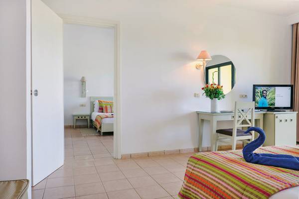 Hotelzimmer im Aldiana Club Djerba Atlantide mit Bett, Schreibtisch, Fernseher und Deko.