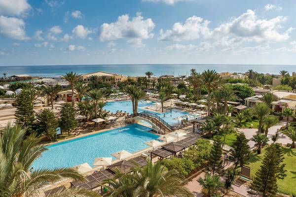 Luftaufnahme des Aldiana Club Djerba Atlantide Hotels mit Swimmingpools, Palmen und Meer im Hintergrund.