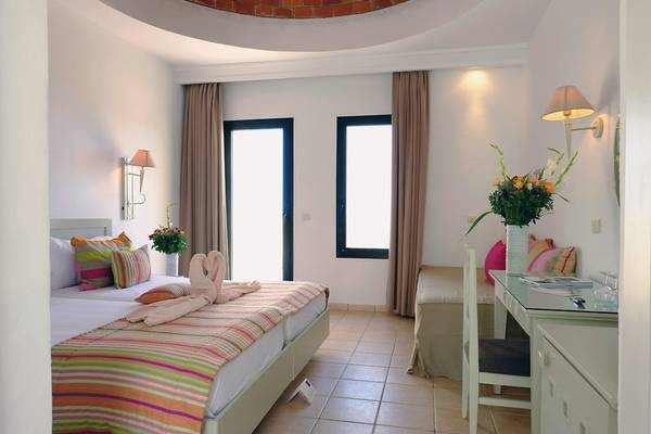 Schlafzimmer im Aldiana Club Djerba Atlantide Hotel mit zwei Betten, Fenstern und Dekor.