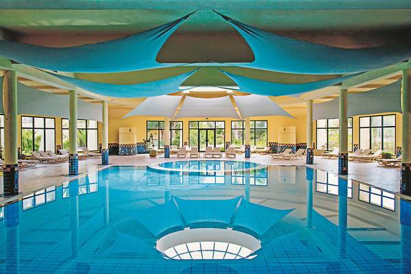 Innenpool des Aldiana Club Djerba Atlantide mit blauen Sonnensegeln.