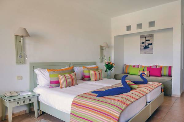 Hotelzimmer im Aldiana Club Djerba Atlantide mit zwei Betten, bunten Kissen und Deko-Schwänen.