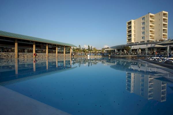 Außenpool des Arina Beach Resorts mit Gebäuden und Liegestühlen.