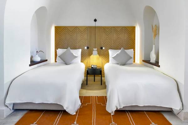 Doppelbett Zimmer Inneneinrichtung im Mövenpick Resort El Quseir mit weißen Wänden, Holzkopfteil, und modernen Möbeln.
