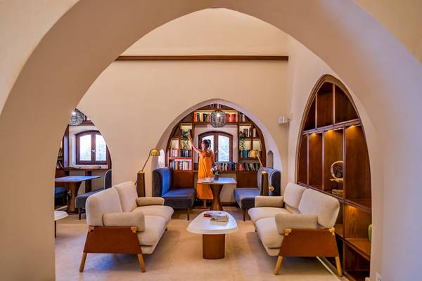 Lounge-Bereich im Mövenpick Resort El Quseir mit Frau in orangem Kleid und Bücherregalen.