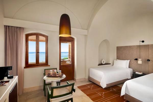 Hotelzimmer des Mövenpick Resort El Quseir mit Meerblick, zwei Betten, Tisch und Fenstern