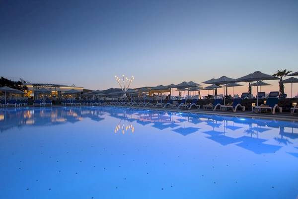 Arina Beach Resort Pool bei Nacht mit blauem Wasser und Sonnenliegen