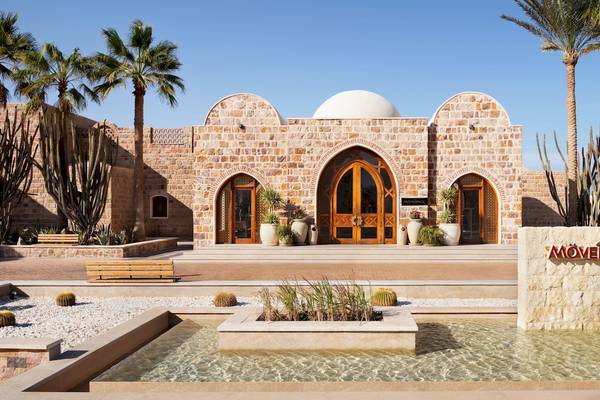 Außenansicht des Mövenpick Resorts El Quseir mit Brunnen, Palmen und Steingebäuden.