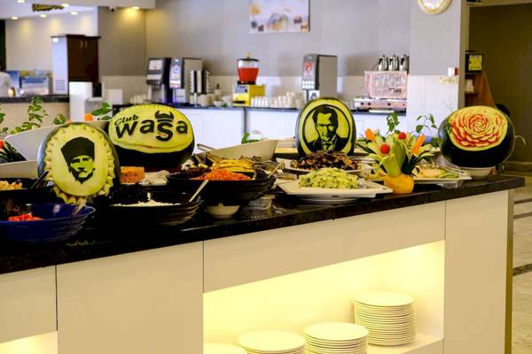 Buffet im Club Wasa Holiday Village mit verschiedenen Gerichten und Wassermelonen-Porträts.