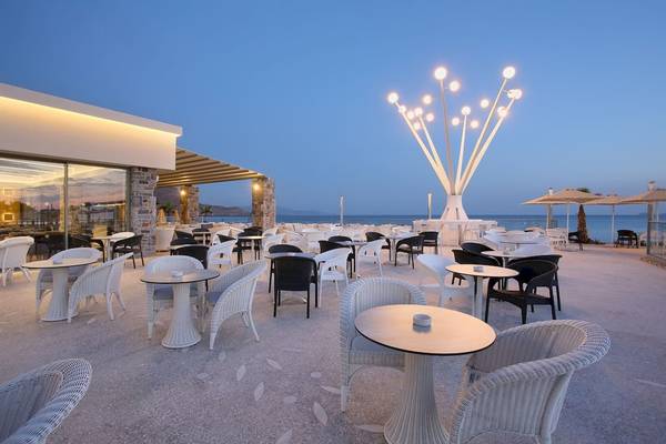 Außenterrasse des Arina Beach Resorts mit weißen Stühlen und Tischen bei Sonnenuntergang.
