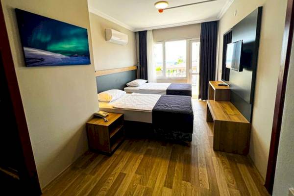Doppelzimmer im Club Wasa Holiday Village mit zwei Betten, Fernseher, Nachttischen und einem Fenster mit Blick nach draußen.