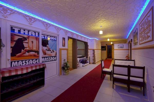 Innenbereich des Club Wasa Holiday Village mit rotem Teppich, weißen Bänken und Massage-Werbetafel.