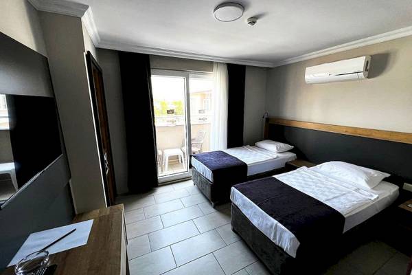 Innenansicht eines Hotelzimmers im Club Wasa Holiday Village mit zwei Betten, einem Schreibtisch und einer Klimaanlage.