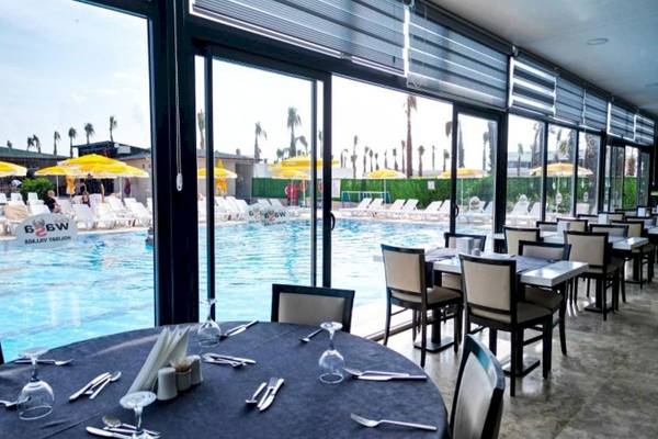 Innenansicht des Restaurants im Club Wasa Holiday Village mit Blick auf den Swimmingpool und Sonnenliegen.
