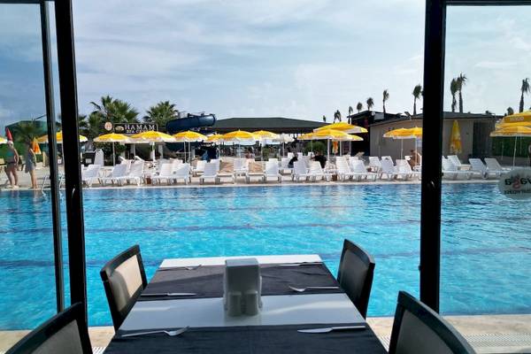 Blick auf den Poolbereich des Club Wasa Holiday Village mit Sonnenschirmen und Liegestühlen