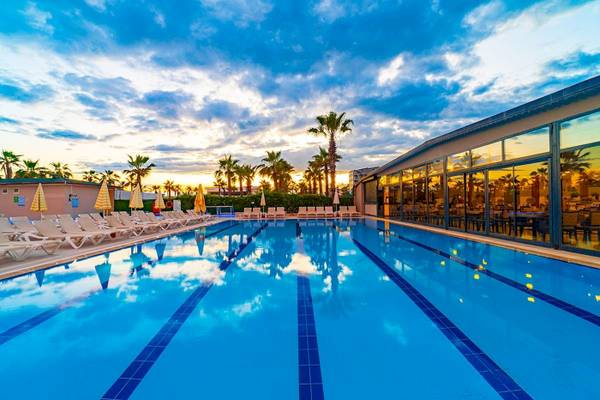 Ein Swimmingpoolbereich des Club Wasa Holiday Village mit Sonnenliegen und Sonnenschirmen.