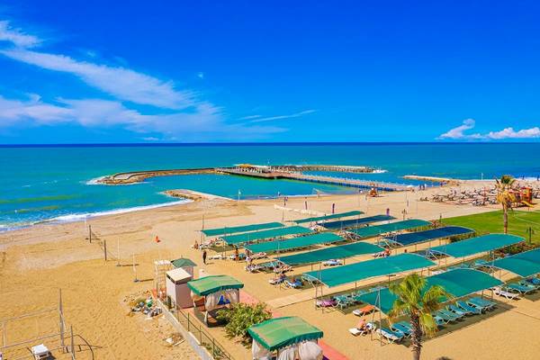 Luftaufnahme des Club Wasa Holiday Village Strands mit vielen Sonnenliegen und Sonnenschirmen