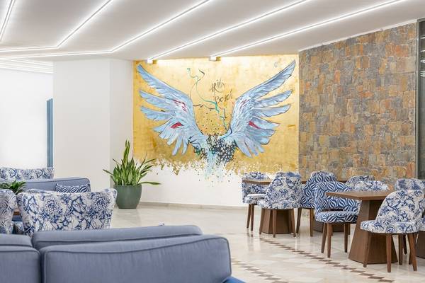 Lounge-Bereich im Arina Beach Resort mit Stühlen und Tischen sowie einer Wandmalerei.