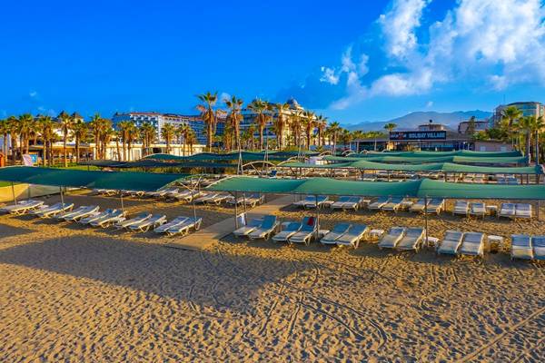 Strandbereich des Club Wasa Holiday Village mit vielen Liegestühlen und Sonnenschirmen.