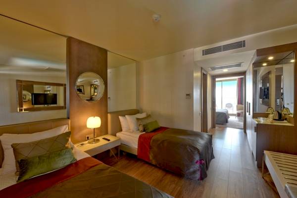 Innenansicht eines Hotelzimmers im Side Star Elegance mit zwei Betten, Nachttischen und einem großen Spiegel.