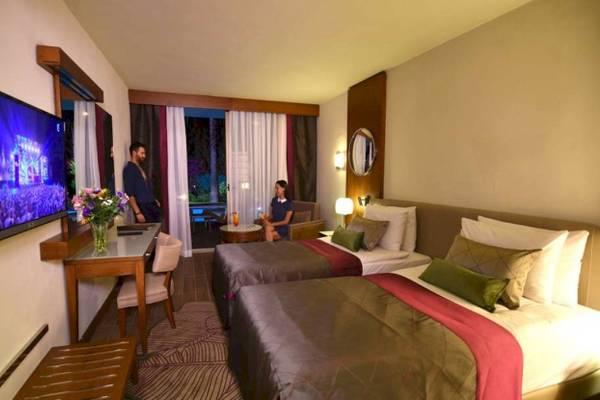 Doppelzimmer im Side Star Elegance Hotel mit Fernseher, Schreibtisch und zwei Betten.