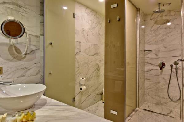 Badezimmer im Side Star Elegance Hotel mit Marmorwänden, einer Dusche und einem Waschbecken.