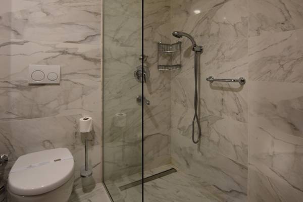 Badezimmer im Side Star Elegance Hotel mit einer Glasdusche und einer Toilette.