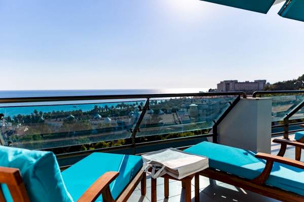 Terrasse mit Meerblick im Side Star Elegance Hotel mit blauen Möbeln und einem Ausblick auf das Meer und die Stadt.