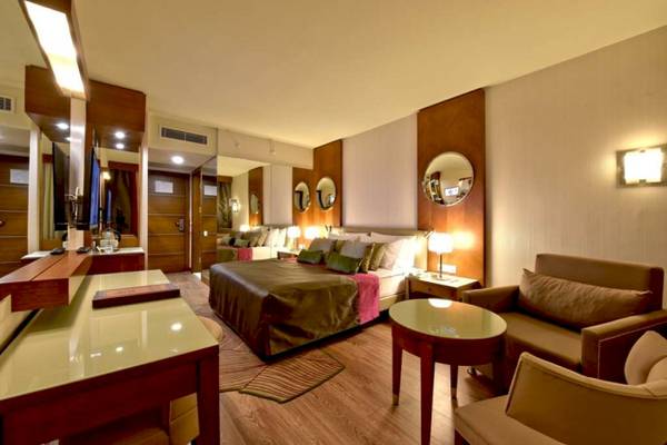 Innenansicht eines Hotelzimmers von Side Star Elegance mit Bett, Schreibtisch und Sofas.