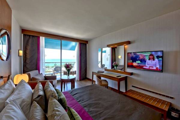Hotelzimmer mit Meerblick, Fernseher, Bett, Sofa, Tisch und Dekor.