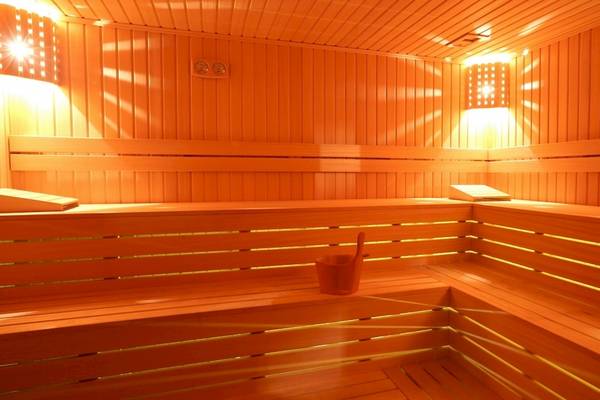 Innenansicht der Sauna im Side Star Elegance Hotel mit Holzbänken, Lichtern und einem Eimer.