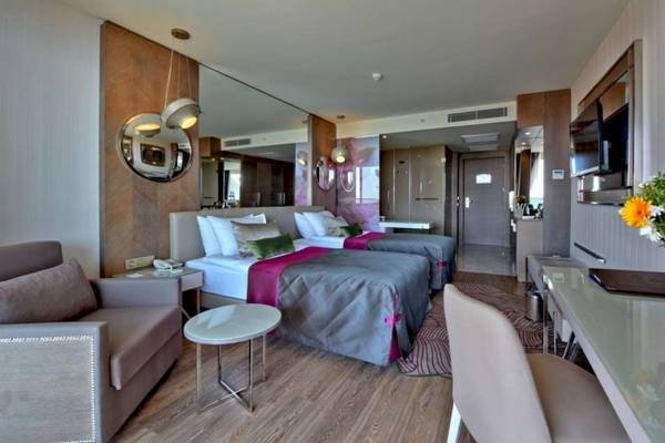 Suite-Zimmer im Side Star Elegance Hotel mit zwei Betten, Sofa, Schreibtisch und Fernseher.