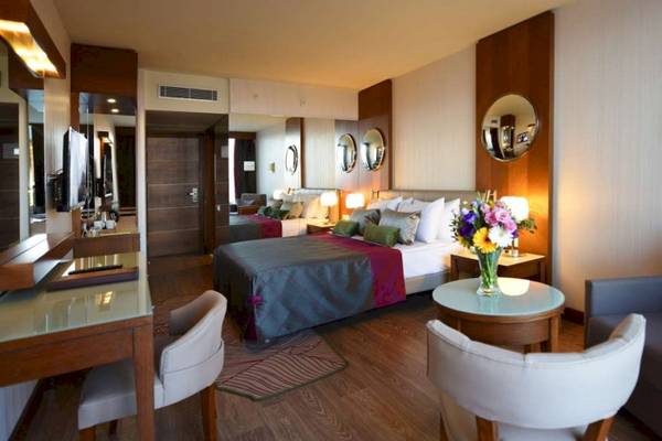 Innenansicht eines Zimmers im Side Star Elegance Hotel mit zwei Betten, Schreibtisch und Stühlen.