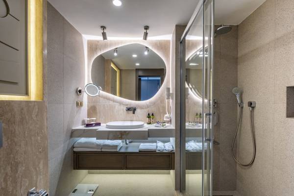 Das Badezimmer des Side Star Elegance Hotels mit einer großen ovalen Spiegel, einer Regendusche und einem Waschbecken.