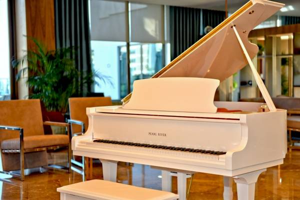 Ein weißes Klavier steht im Foyer des Side Star Elegance Hotels neben zwei Sesseln und einer Pflanze.